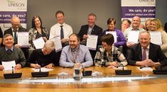 council and union representatives gather at desk and signing the charter