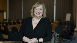 Christina McAnea leans on a railing with her hands clasped, wearing a black top