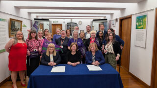 Christina McAnea at a table with the leader and CEO of Newcastle City Council, to sign a Disability Employment Charter, with members standing behind them