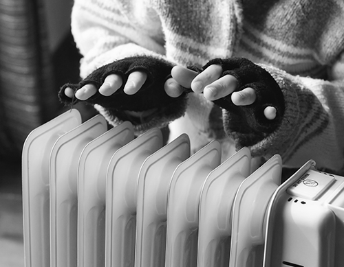 hands in fingerless gloves over a heater