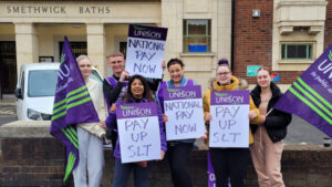 Workers on strike holding signs that read 'Pay up SLT'