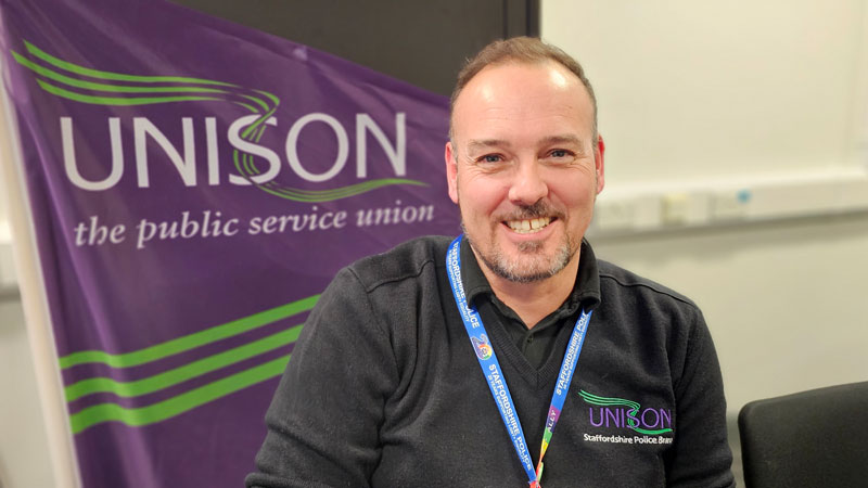 Rob Birch, sitting in front of a UNISON banner