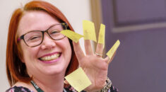 Female UNISON member smiling, with stickies on her fingers, at a UNISON learning event