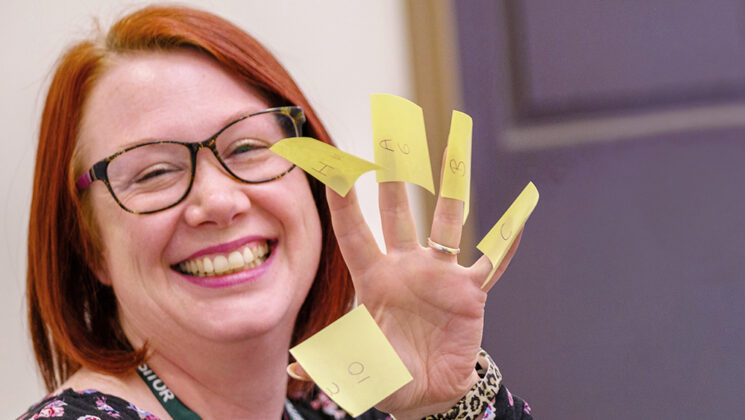 Female UNISON member smiling, with stickies on her fingers, at a UNISON learning event