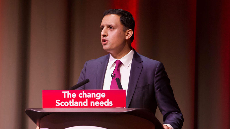 Anas Sarwar speaking in front of a podium with the words 'The change Scotland needs'