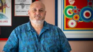 Andy Hewston stands in a blue shirt