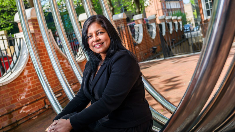 Shantha David, sitting on a landscape sculpture at UNISON Centre