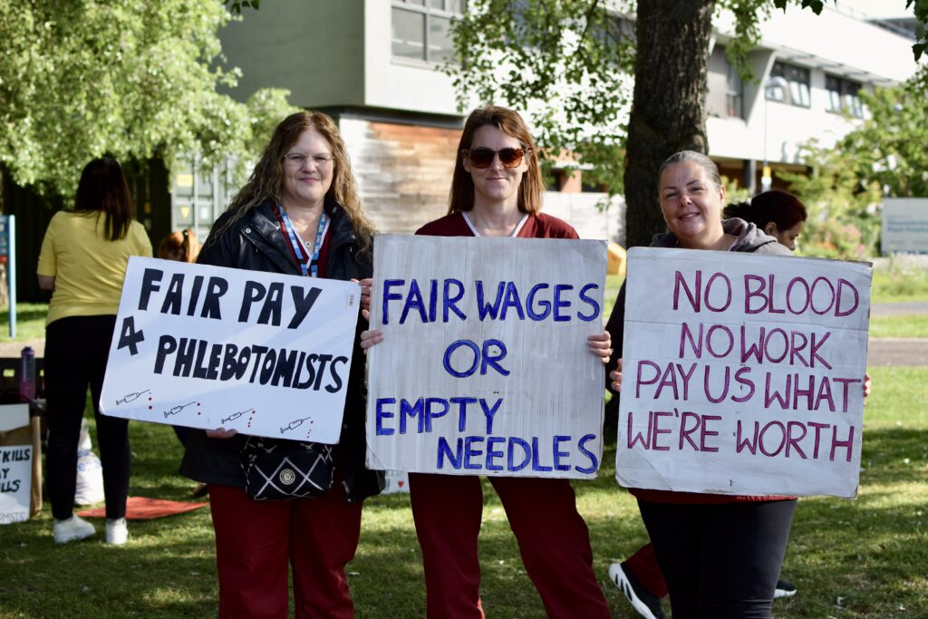 Phlebotomists hold placards on the picket line