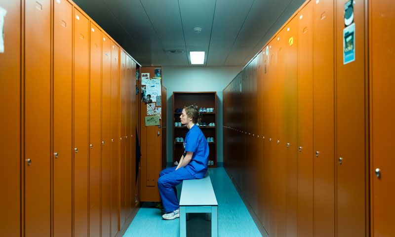 A nurse sits alone in an empty changing room