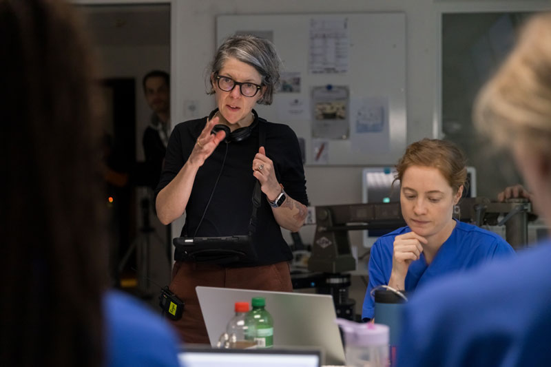 Photograph of Petra film director Volpe on the set of her film, with actress Leonie Benesch in her nurse's uniform sitting in front of her
