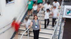 Clara Mason standing on some stairs, surrounding by children running down the stairs. The children are out of focus
