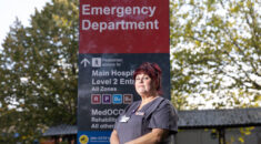 Portrait of Diane Coombs in front of a hospital entrance sign.