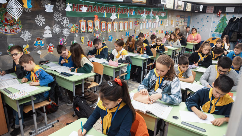 A makeshift school classroom, with young boys and girls working at their desks