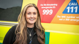 Claire Hunter-Girdler smiling in front of an ambulance