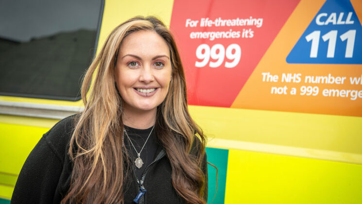 Claire Hunter-Girdler smiling in front of an ambulance